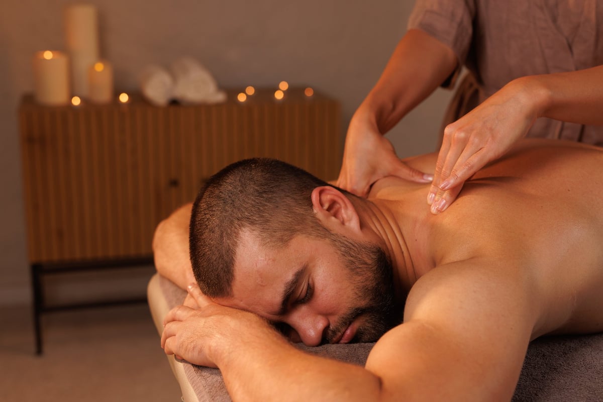 Close-up of a female massage therapist massaging a male client's shoulders and back