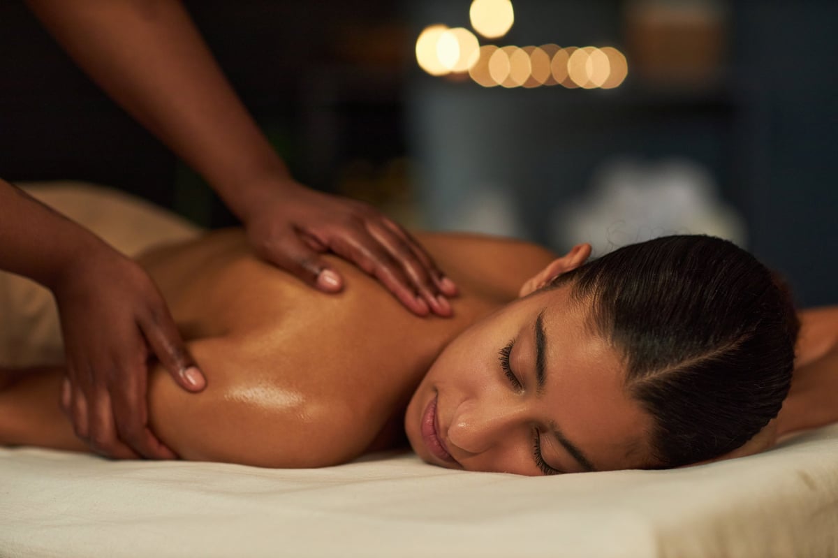 Woman relaxing while receiving a massage in a spa with candles