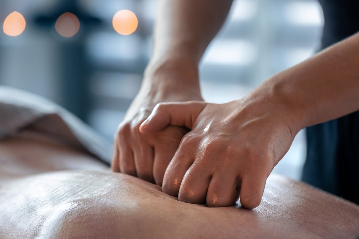 Hands pressing evenly on an oiled back during a massage